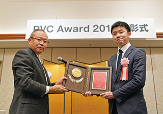 写真：横田実行委員長（塩ビ工業・環境協会会長）から表彰盾を贈られる後藤さん（右）。